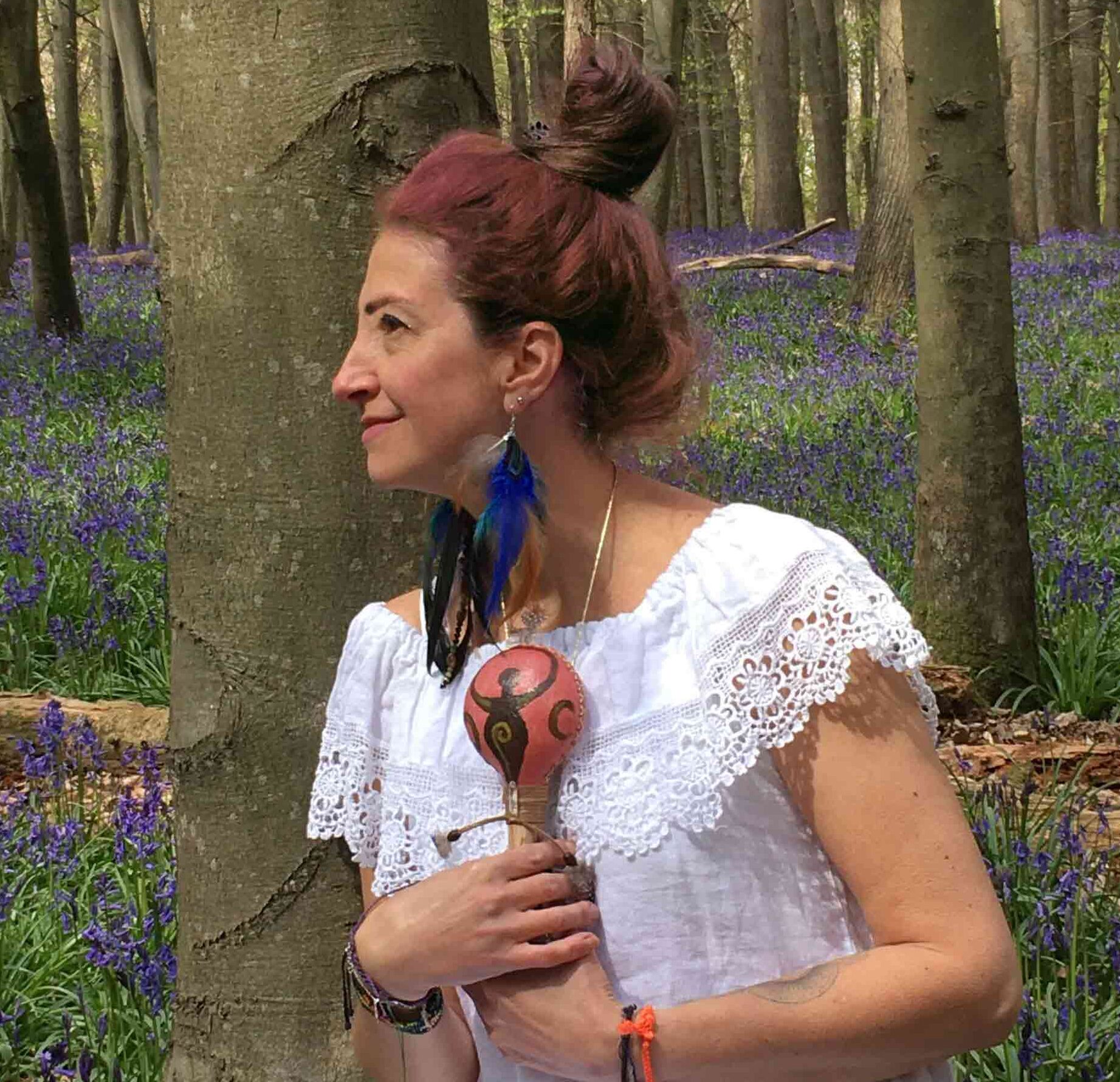 Gloria Urech in woods holding a maraca